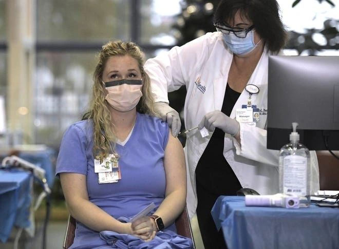 Doctor administering COVID-19 vaccine to hospital worker